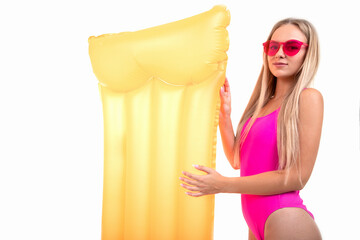 Obraz premium A beautiful blonde woman in a pink swimsuit and glasses holds an air mattress. Summer holiday..