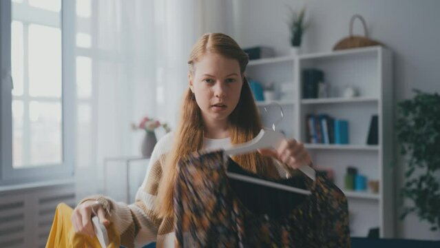 Pretty teenage girl choosing an outfit in front of mirror, first date, going out