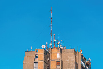 Communication antennas and satellite dishes on top of high residential building - obrazy, fototapety, plakaty