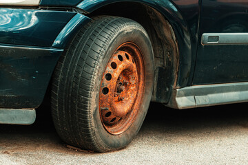 Fototapeta na wymiar Old rusty car wheel rim and worn tire
