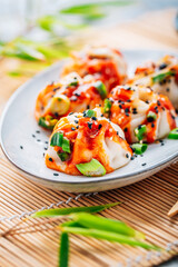 Steamed dumplings Dim Sum with  hot Sriracha sauce and green onions and sesame seeds
