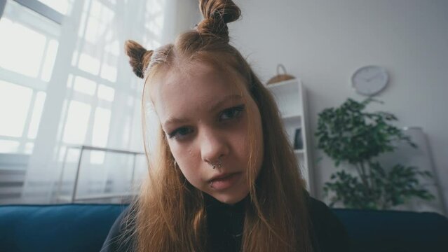 Portrait of teen girl with face piercings sitting on sofa, rebellion, puberty