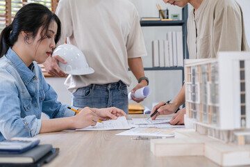 Obraz premium Engineers discuss a blueprint while checking information on a tablet computer in a office.