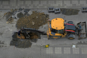 An excavator repairs sewer storm hatches ata street on a summer day. Selective Focus Machine. Top...