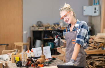 Carpenter woman professional skill using electric drill for wood in carpentry shop