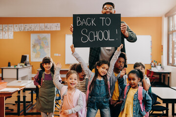 Teacher and students holding up a back to school sign in a classroom