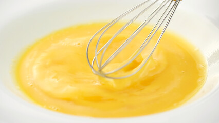 Stirring eggs with whisk in white plate