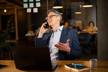 Businessman in office. Handsome man talking on phone at work.