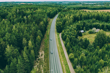 Aerial view of road with cars through green summer woods in Finland