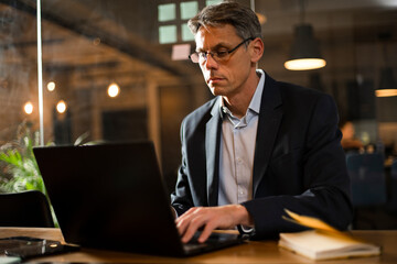 Businessman working with laptop at office. Businessman sitting at office desk working on laptop computer..