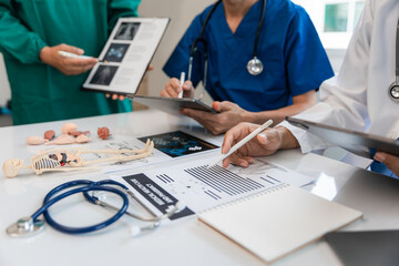 Medical team meeting with doctors in white lab coats and surgical gowns sitting at table discussing patient history. success of medical health care The concept of working with a doctor. Close up.