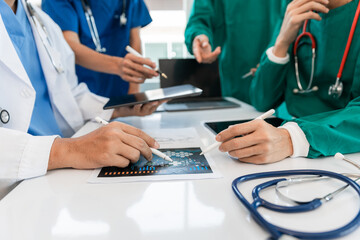 Medical team meeting with doctors in white lab coats and surgical gowns sitting at table discussing patient history. success of medical health care The concept of working with a doctor. Close up.