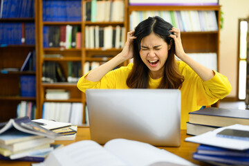 Stressed female college student having serious computer problem or feeling tired of studying for...