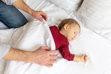 Father covering her sleeping baby with blanket