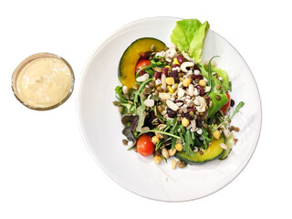 Isolated mixed nut and vegetable salad with salad dressing on white background