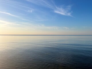 Fototapeta premium Blue sea horizon with some light clouds, seascape background