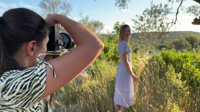 Photographer taking photo of smiling woman with bouquet of dry grass in park