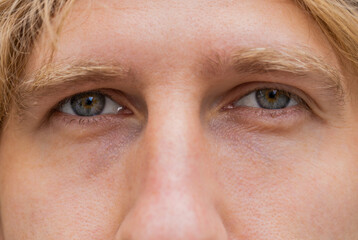 Extreme close-up macro portrait of face. Young adult beautiful redhead man's eyes looking at...