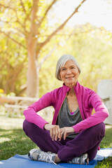 Naklejka na ściany i meble Older woman sitting on yoga mat outdoors