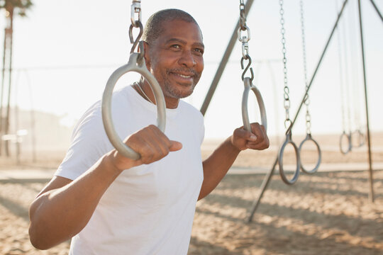 Older man holding exercise rings on beach