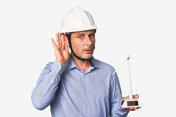 A middle-aged architect man holding a windmill model trying to listening a gossip.