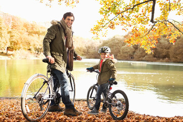 Fototapeta premium Father and son sitting on bicycles in park
