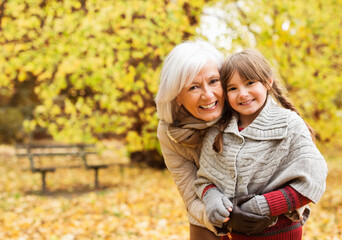 Older woman and granddaughter smiling in park