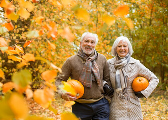 Older couple carrying pumpkins in park