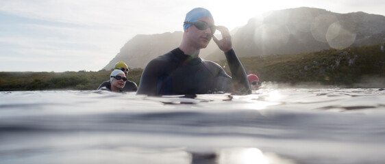 Triathletes in wetsuits standing in water