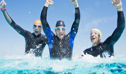 Triathletes in wetsuits splashing in waves