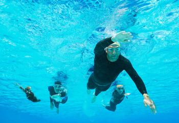 Triathletes in wetsuits underwater