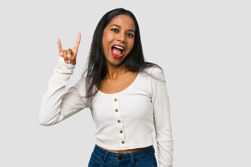 Young Indian woman cut out isolated on white background showing a horns gesture as a revolution concept.