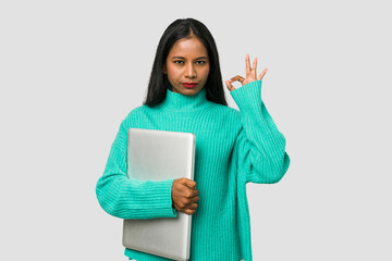 Fototapeta premium Young indian woman holding a laptop isolated on white background
