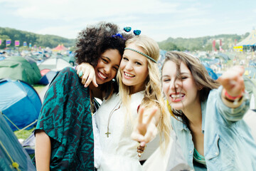 Friends hugging outside tents at music festival