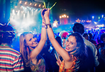 Portrait of cheering women with glow sticks at music festival