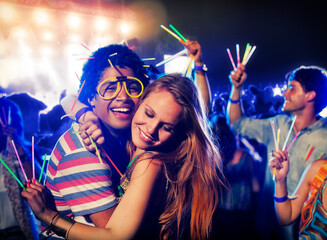 Couple with glow sticks hugging at music festival