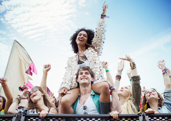 Cheering woman on man shoulders at music festival - obrazy, fototapety, plakaty