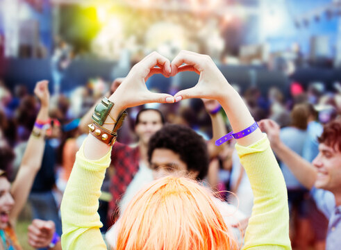 Woman forming heart-shape with hands at music festival