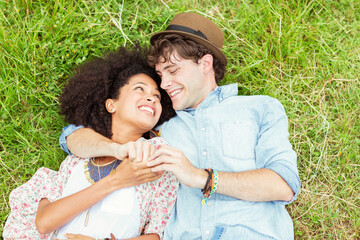 Happy couple holding hands and laying in grass
