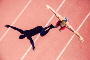 Track and field athlete jumping on track with arms outstretched