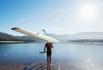 Man carrying rowing scull into lake