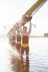 Rowing team carrying scull overhead in lake - obrazy, fototapety, plakaty