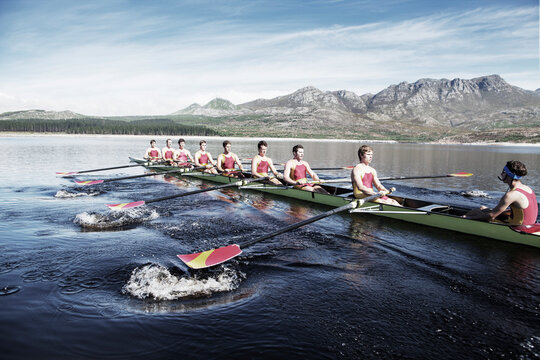 Rowing team rowing scull on lake