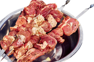 Raw fresh meat with spices on skewers in an iron bowl for barbecue, grill