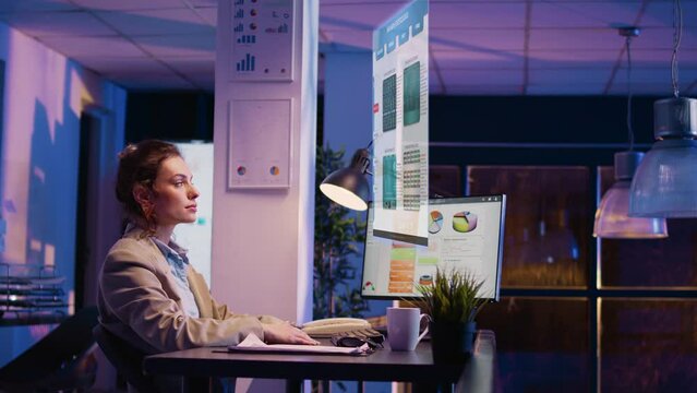 Office worker reviewing results hologram at night, looking at holographic images of company analytics. Executive employee using archive information, artificial intelligence reports.