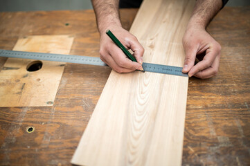 Carpenter holding a measure tape on the work bench