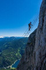 Woman climbs high on rock. Pretty, female climber on a via ferrata - climbing on a rock in Donnerkogel Klettersteig. Taken from mountain Donnerkogel near Hoher Dachstein ehrwald austria alps