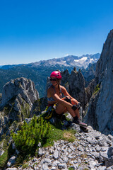 Obraz premium Woman sitting on mountain looking away and smiling. Female mountain climber looking at the view and smiling.