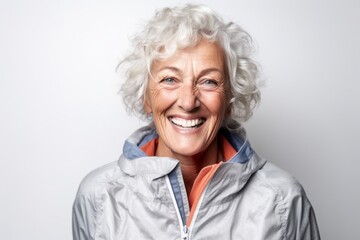 Conceptual portrait photography of a happy mature woman wearing a lightweight windbreaker against a white background. With generative AI technology