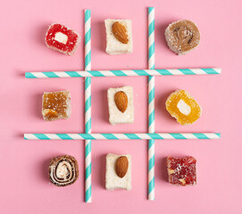 Tic-tac-toe made of Turkish delight sweets and straws. Flat lay. Sweet food concept.